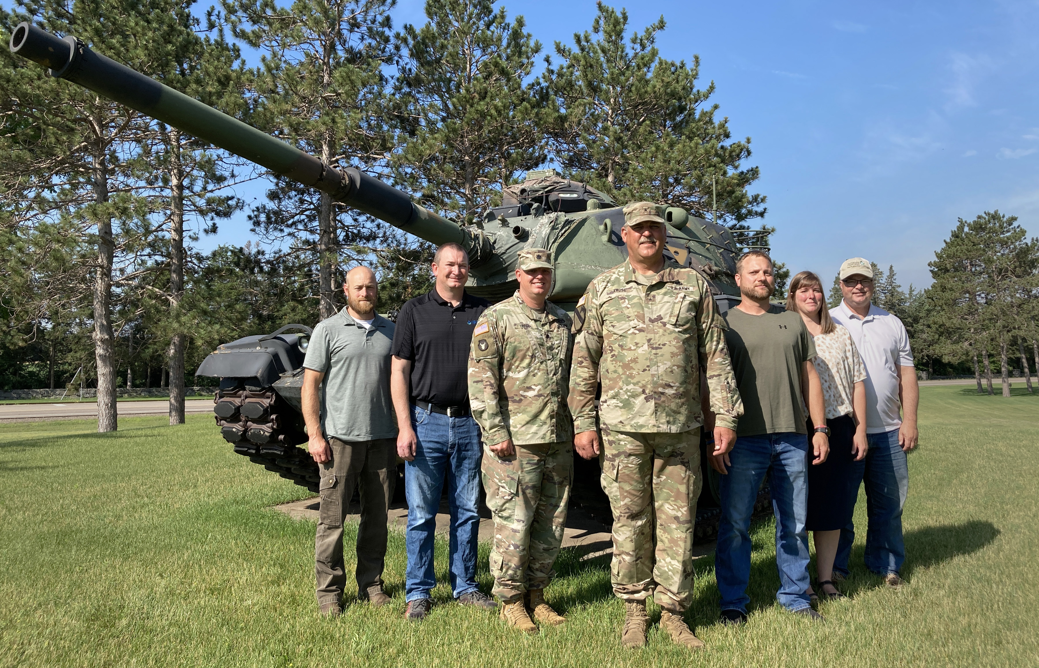 Seven people stand in front of a tank
