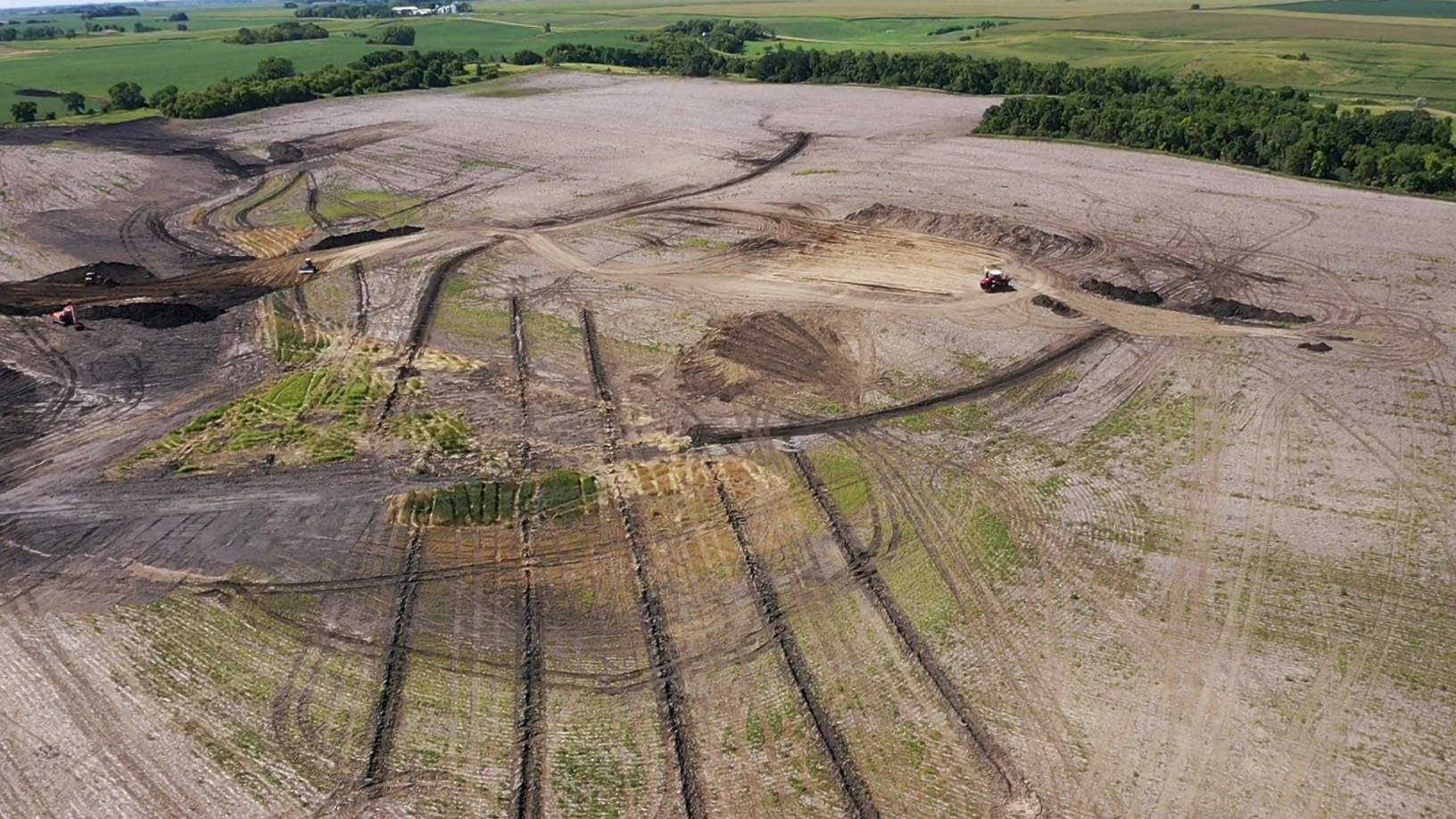 In an aerial view, trenches appear as long dark lines in a field.