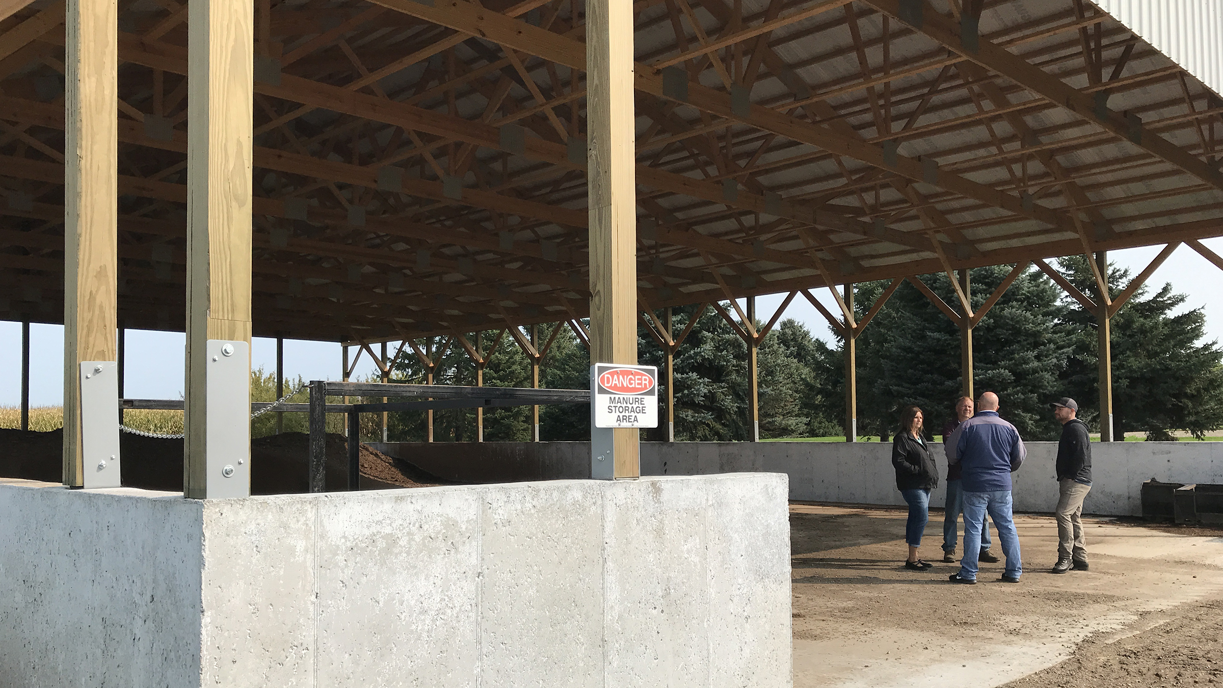 three people standing under a covered manure storage area