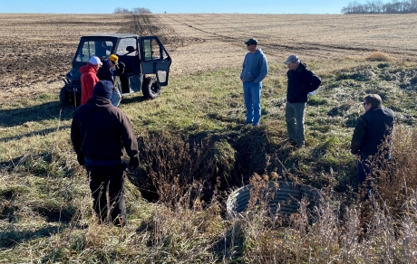 A small group of people stands at the edge of a field